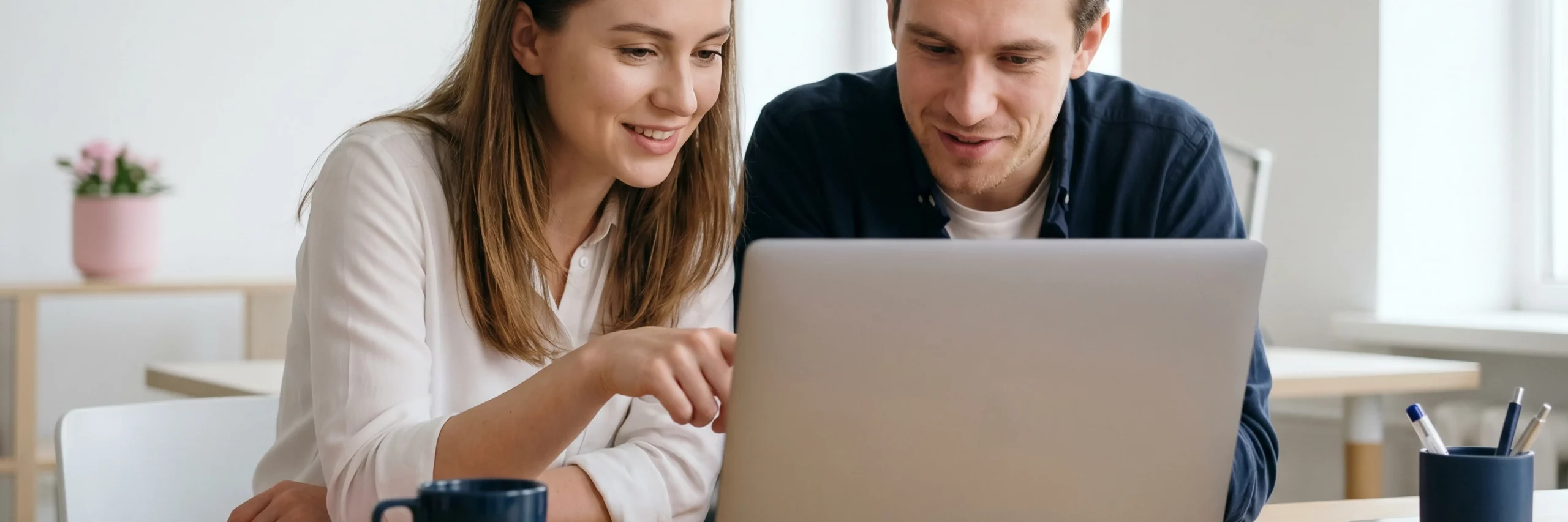 Zwei Designer besprechen ein Konzept an einem Laptop.