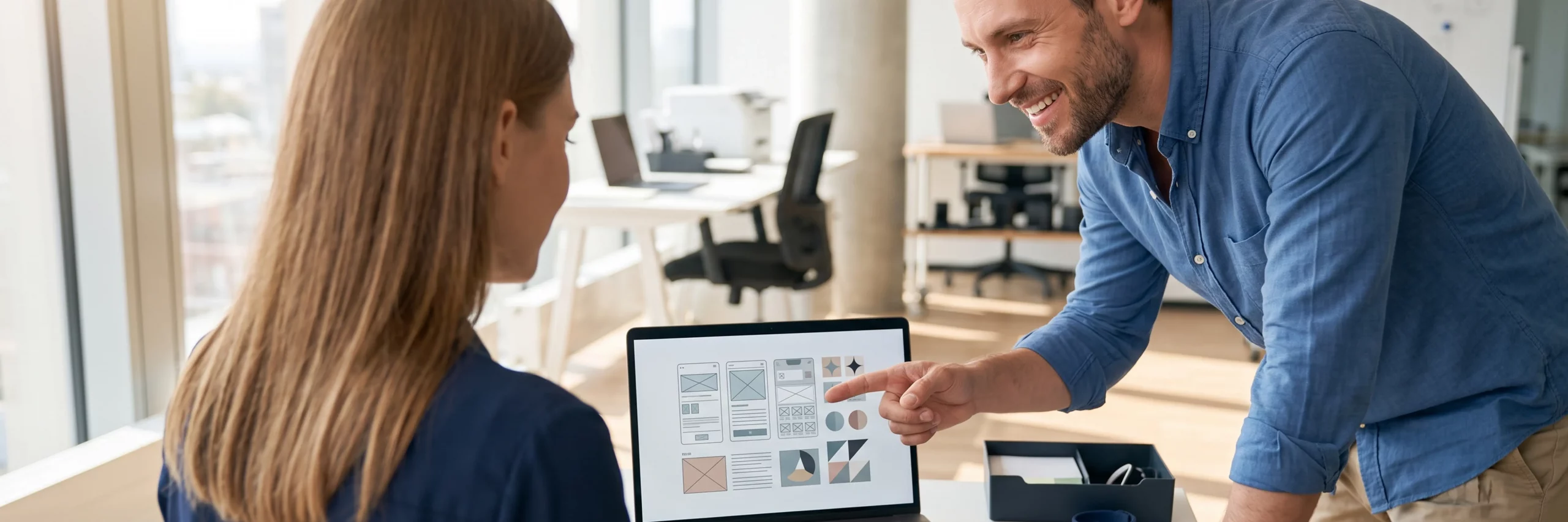 Zwei Designer überprüfen zufrieden abstrakte Gestaltungselemente am Laptop